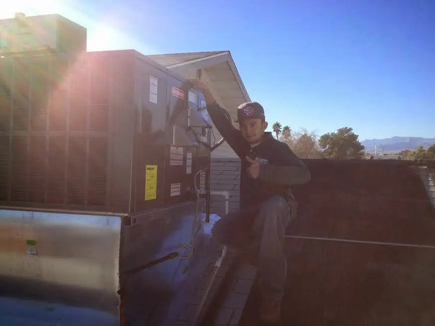 HVAC technician performing Heat Pump Repair on a rooftop unit in Mayfield
